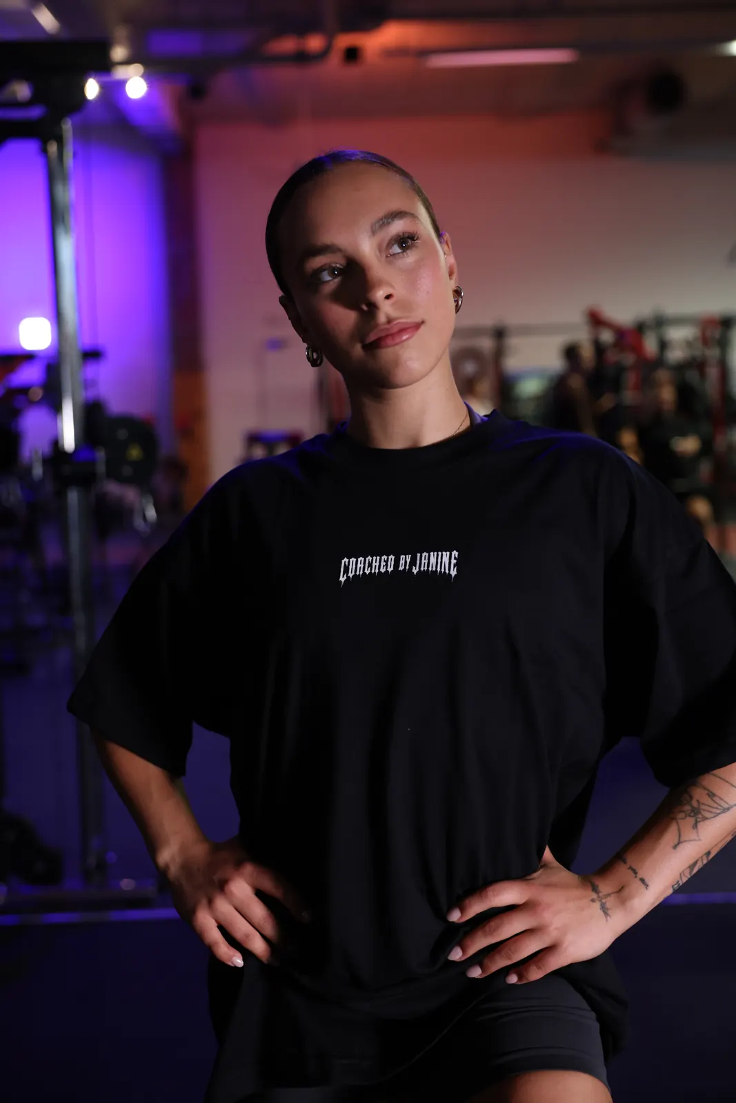 The front: a small Coached-by-Janine chest print, nothing else — worn facing the camera